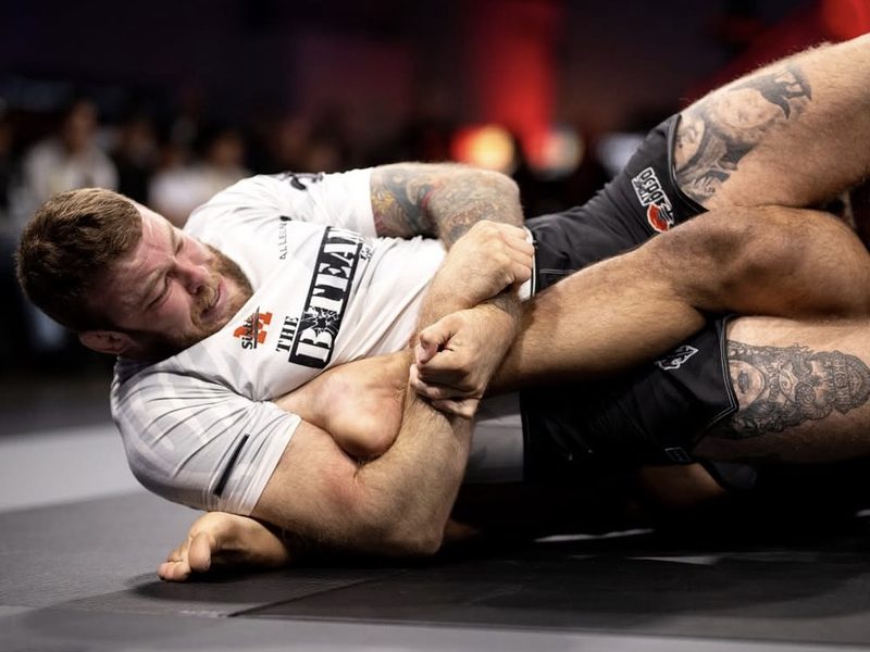 Declan Moody attacking a leg lock on the mat during a match
