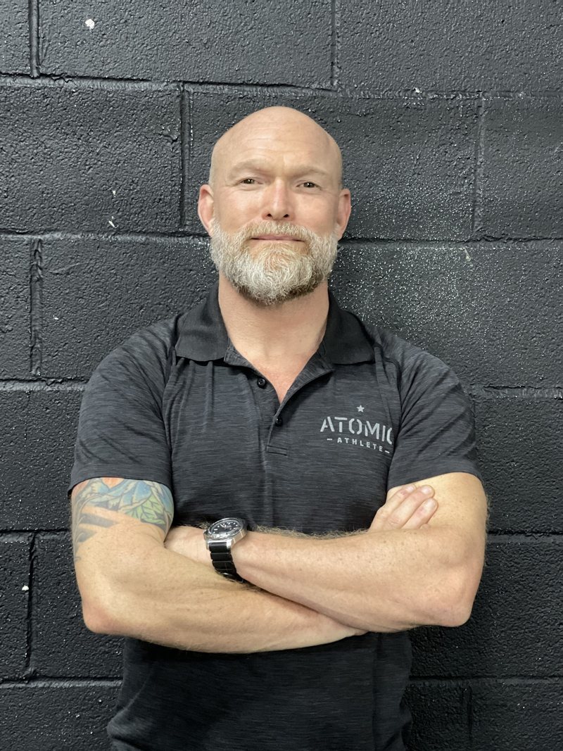 Tod Moore, co-owner of Atomic Athlete, arms crossed in an Atomic Athlete polo
